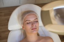 Жінка отримує косметичні процедури, лежачи на ліжку салону у вітальні — стокове фото