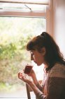 Vista lateral da mulher tomando um chá em casa — Fotografia de Stock
