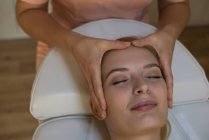 Косметолог дає масаж обличчя жінці-клієнту у вітальні — стокове фото