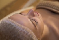Женщина получает косметические процедуры, лежа на кровати салона — стоковое фото