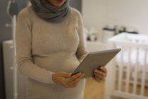 Середина вагітної жінки, використовуючи цифровий планшет в магазині — стокове фото