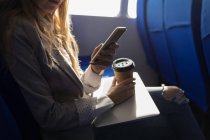Mittelteil der Frau benutzt Handy beim Kaffee im Kreuzfahrtschiff — Stockfoto