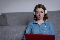 Mujer joven usando un ordenador portátil en la sala de estar en casa - foto de stock