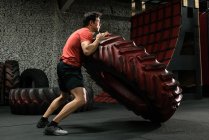 Homem muscular lançando pneu no ginásio — Fotografia de Stock