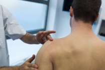 Физиотерапевт накладывает повязку на плечо пациента в клинике — стоковое фото