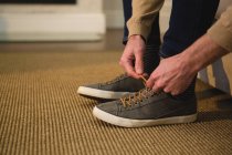 Низька частина людини, що зв'язує шнурки у вітальні вдома — стокове фото