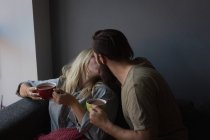 Couple kissing each other while having coffee in living room at home — Stock Photo