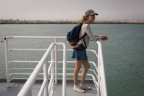 Beautiful woman with backpack standing on cruise ship — Stock Photo