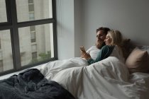 Пара за допомогою мобільного телефону в спальні вдома — стокове фото