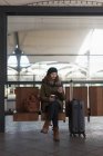 Жінка з чашкою кави за допомогою мобільного телефону в зоні очікування — стокове фото