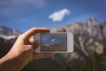 Крупним планом чоловік фотографує гори з мобільним телефоном — стокове фото