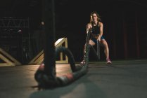 Mujer muscular haciendo ejercicio con cuerda de batalla en el gimnasio - foto de stock
