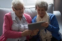 Amici anziani che utilizzano tablet digitale a casa — Foto stock
