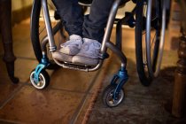 Sección baja del hombre discapacitado en silla de ruedas en casa - foto de stock