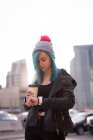 Mujer con estilo comprobar el tiempo en smartwatch mientras toma café - foto de stock