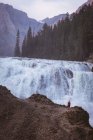 Человек с рюкзаком смотрит на водопад — стоковое фото