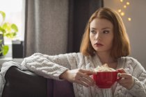 Молода жінка має каву вдома — стокове фото