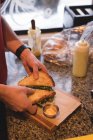Primer plano del camarero masculino preparando sándwich en la cafetería - foto de stock