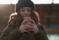 Woman in winter clothing using mobile phone in railway station — Stock Photo