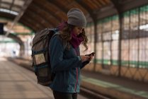 Jovem usando telefone celular na estação ferroviária — Fotografia de Stock