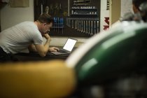 Nachdenklicher Mechaniker mit Laptop in Garage — Stockfoto