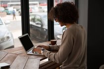 Вид сбоку на человека, использующего ноутбук в кафе — стоковое фото