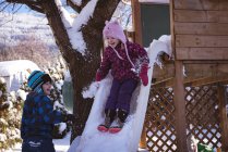 Siblings playing in snow covered playground during winter — Stock Photo