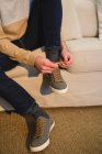 Низкая часть человека завязывая шнурки в гостиной на дому — стоковое фото