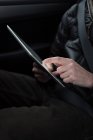Sección media del hombre usando tableta digital en un coche - foto de stock