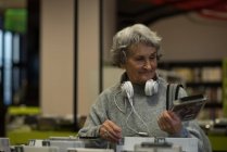 Mujer mayor eligiendo un casete de dvd en la biblioteca - foto de stock