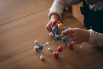 Sección media de la niña experimentando modelo de molécula en casa - foto de stock