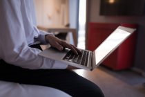 Seção média de homem de negócios usando um laptop na cama no quarto de hotel — Fotografia de Stock