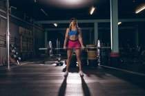 Подходящая женщина поднимает штангу в спортзале — стоковое фото