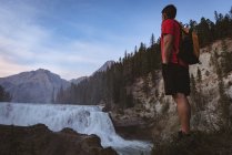 Man with backpack standing near waterfall — Stock Photo
