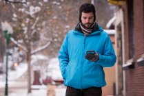 Man using mobile phone in town during winter — Stock Photo