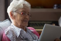 Mulher idosa usando tablet digital em casa — Fotografia de Stock