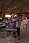 Mujeres discutiendo sobre documentos en taller de carpintería - foto de stock