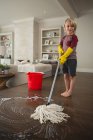 Хлопчик миє підлогу мопедом вдома — стокове фото