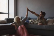 Casal dando mais cinco uns aos outros na sala de estar em casa — Fotografia de Stock