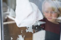 Ventana de limpieza de niño con trapo en casa - foto de stock