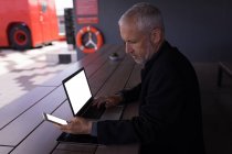 Бізнесмен використовує мобільний телефон під час роботи на ноутбуці в готелі — стокове фото