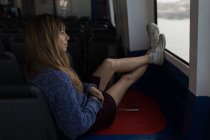 Nachdenkliche Frau sitzt in Kreuzfahrtschiff am Fenster — Stockfoto