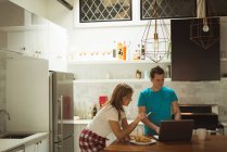 Couple using laptop and mobile phone in kitchen art home — Stock Photo