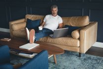 Бизнесмен, использующий ноутбук на диване в офисе — стоковое фото