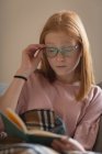 Mädchen liest zu Hause im Wohnzimmer ein Buch — Stockfoto