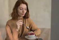 Удумлива жінка з десертом у кафе — стокове фото