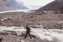 Männlicher Wanderer mit Rucksack wandert an einem sonnigen Tag in Flussnähe — Stockfoto