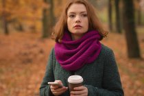Frau benutzt Handy beim Kaffeetrinken im Park — Stockfoto
