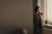 Удумлива жінка, що має каву у вітальні вдома — стокове фото