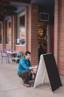 Homme regardant le panneau de menu à l'extérieur du café — Photo de stock